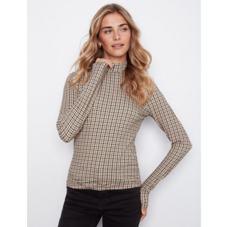 A woman modeling a beige and brown checkered mock neck long-sleeve top with black pants, set against a plain light gray background.