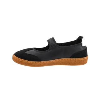 A black slip-on shoe with a textured brown gum sole, shown in a side profile view against a white background.
