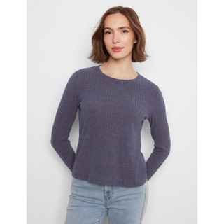 A woman wearing a ribbed long-sleeve knit sweater in a medium grey color, paired with light-wash blue jeans, against a plain light gray studio background.