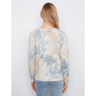 A woman viewed from behind wearing a long-sleeve crewneck top with a light blue and beige palm tree pattern, paired with light blue jeans, against a plain white background.