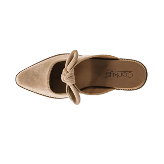 A single taupe suede mule shoe with a pointed toe and a knotted bow detail, shown from a top-down view on a light gray background. The brand name 'Corkys' is visible on the insole.