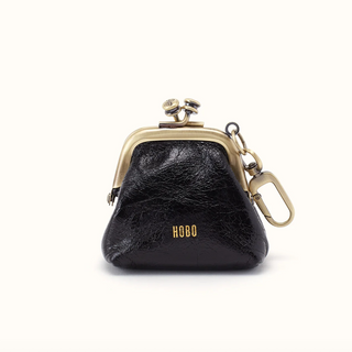 A small black leather coin purse with a gold-tone kiss-lock frame, gold hardware, and the brand name 'HOBO' printed in gold on the front, set against a plain off-white background.