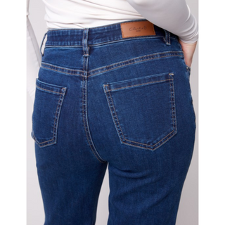 Rear view of a person wearing dark blue denim jeans with a white long-sleeve top, showing the back pockets and waistband.