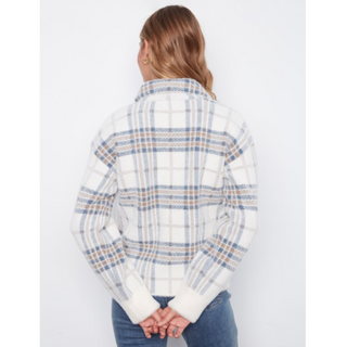 A woman viewed from the back wearing a cropped, long-sleeve plaid knit jacket with a white base and blue and tan stripes, paired with blue jeans against a plain white background.