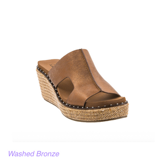 A metallic bronze brown leather wedge slide sandal with a braided jute platform sole and white contrast stitching, shown on a white background with 'Washed Bronze' text at the bottom.