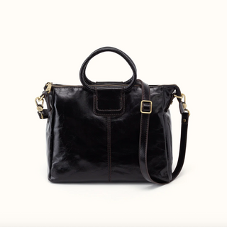 A black patent leather handbag with a top handle, a detachable shoulder strap, and gold-tone hardware, photographed against a clean white background.