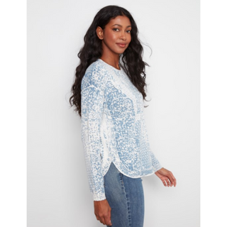 A woman modeling a light blue and white lace long-sleeve top with blue jeans against a plain light gray background.