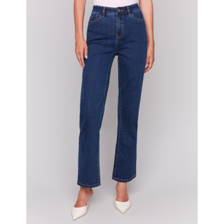 A model wearing dark blue straight-leg jeans and white pointed-toe heels, shown from the waist down against a light gray studio background.