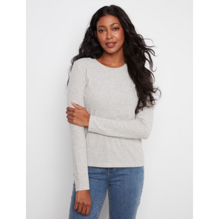 A woman modeling a light gray ribbed knit long-sleeve sweater with blue jeans, standing against a plain light gray background.