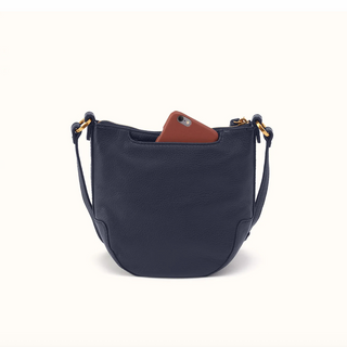 A navy blue pebbled leather shoulder bag with gold-tone hardware, shown on a clean off-white background with a brown phone partially tucked into its top pocket.