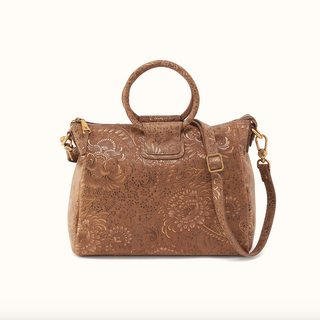 A brown tooled leather handbag with floral embossed patterns, featuring a top handle, a detachable shoulder strap, and gold-tone hardware, shown against a plain white background.