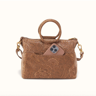 A brown embossed leather handbag with a top handle, a shoulder strap, and a front slip pocket holding a smartphone, shown on a plain light background.