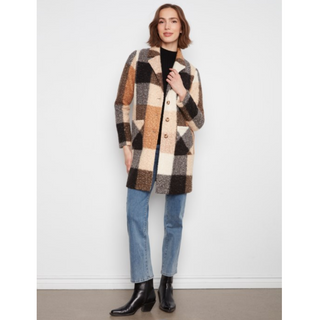 A woman models a mid-length, open-front checkered coat with a fuzzy, textured wool-like appearance. The coat features a large patchwork pattern in beige, brown, black, and cream.