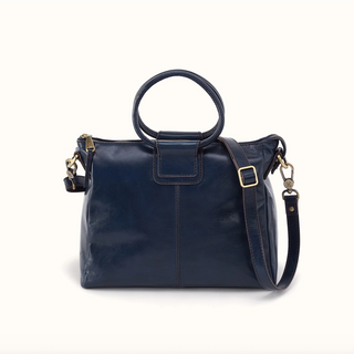 A navy blue leather handbag with a top handle, a detachable shoulder strap, and gold-tone hardware, photographed on a clean off-white background.