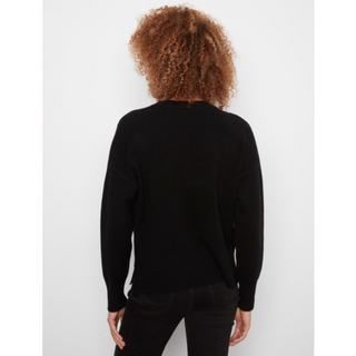 A person shown from the back wearing a black long-sleeve knit sweater and black pants against a plain light gray studio background.