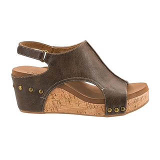 A single women's wedge sandal in dark brown faux leather with a cork-textured wedge heel and platform, featuring brass-tone grommets and an adjustable ankle strap.