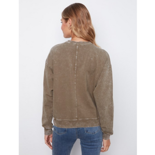 A woman viewed from the back wearing a faded taupe-brown crewneck sweatshirt and blue jeans against a plain white background.