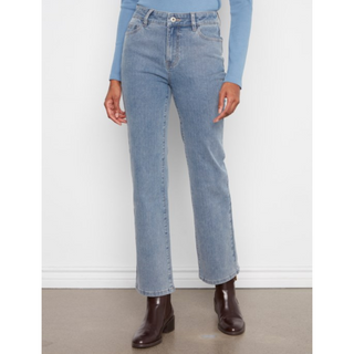 A person wearing light-wash blue denim jeans with a straight-leg or slightly relaxed fit, paired with a light blue long-sleeve top and dark brown ankle boots, standing against a plain white wall.