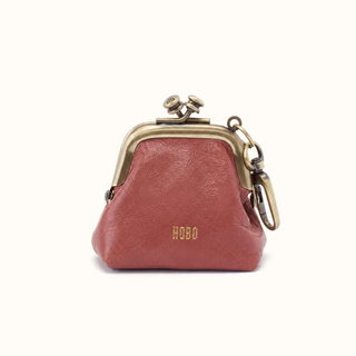 A small burgundy leather kiss-lock coin purse with gold-tone metal hardware and the brand name 'HOBO' embossed on the front, set against a plain off-white background.