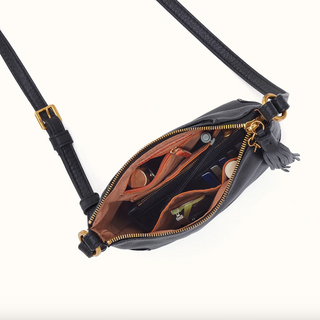 Black leather crossbody bag with gold-tone hardware, shown open to reveal a brown interior organizer, tassel zipper pull, and black strap on a white background.