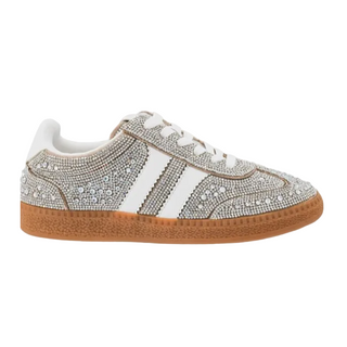 A low-top sneaker embellished with silver rhinestones, featuring white leather side stripes, white laces, and a textured brown gum sole, shown against a plain white background.
