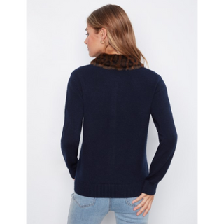 A woman shown from the back wearing a navy blue knit sweater with a brown and black leopard-print faux fur collar, paired with light blue jeans, against a plain white background.